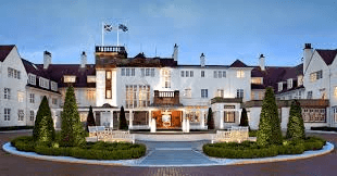 Grand luxury hotel with illuminated courtyard fountain and topiary at dusk